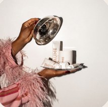 Hand in a pink feathered sleeve presenting skincare products